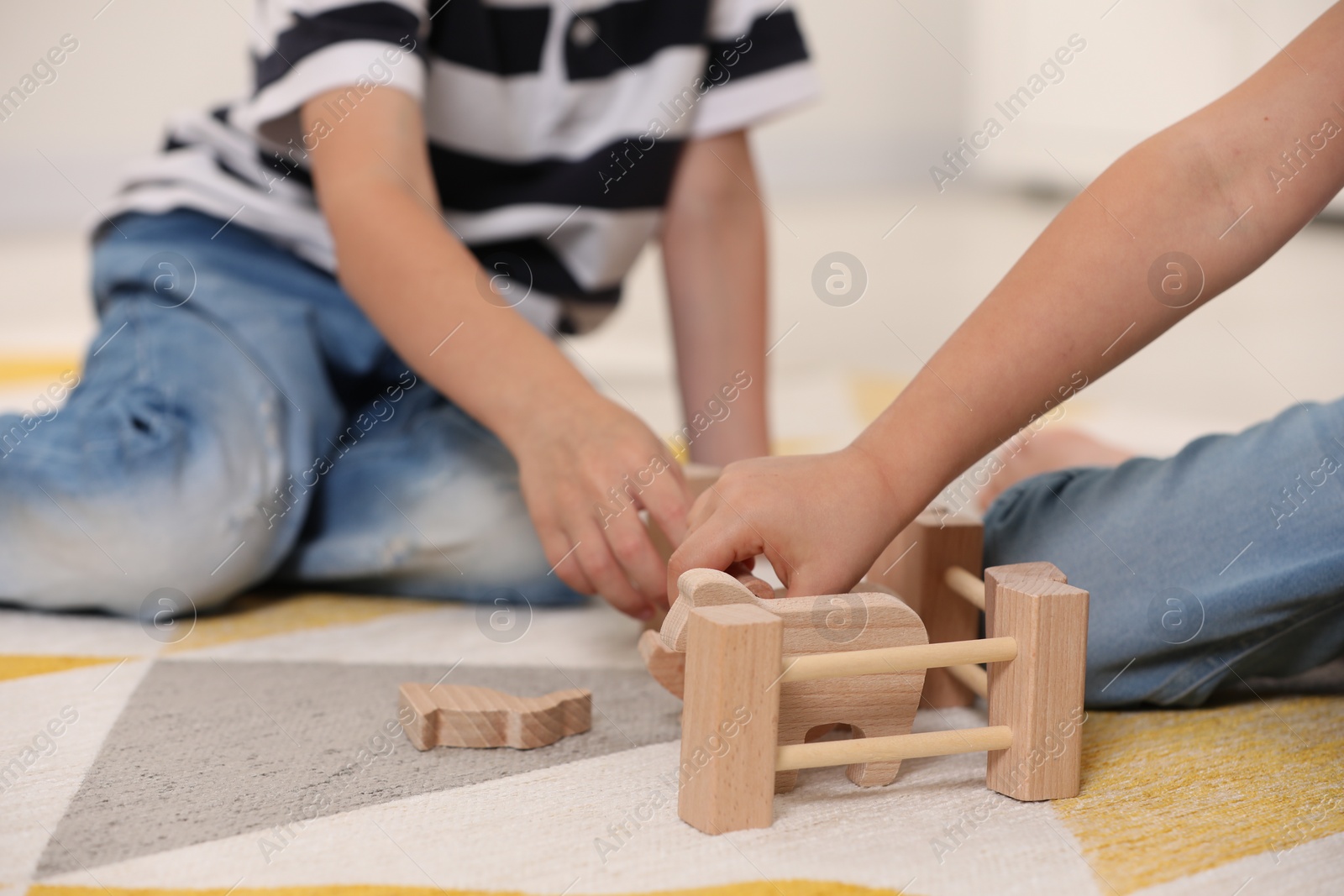 Photo of Little children playing with set of wooden animals indoors, closeup