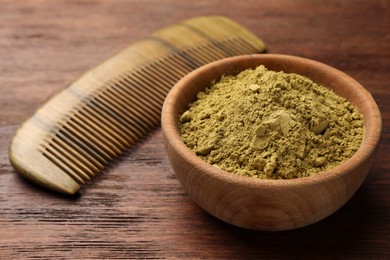 Photo of Bowl of henna powder and comb on wooden table