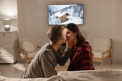 Photo of Lovely couple kissing near fireplace at home