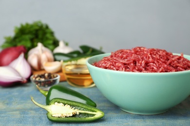 Photo of Fresh raw minced meat and vegetables on blue wooden table