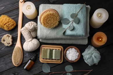 Photo of Flat lay composition with different spa products, burning candles and eucalyptus branches on black wooden table