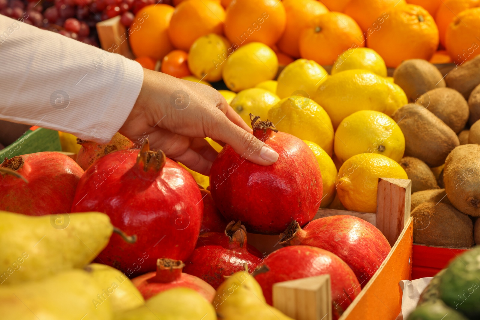 Photo of Woman picking fresh pomegranate at market, closeup