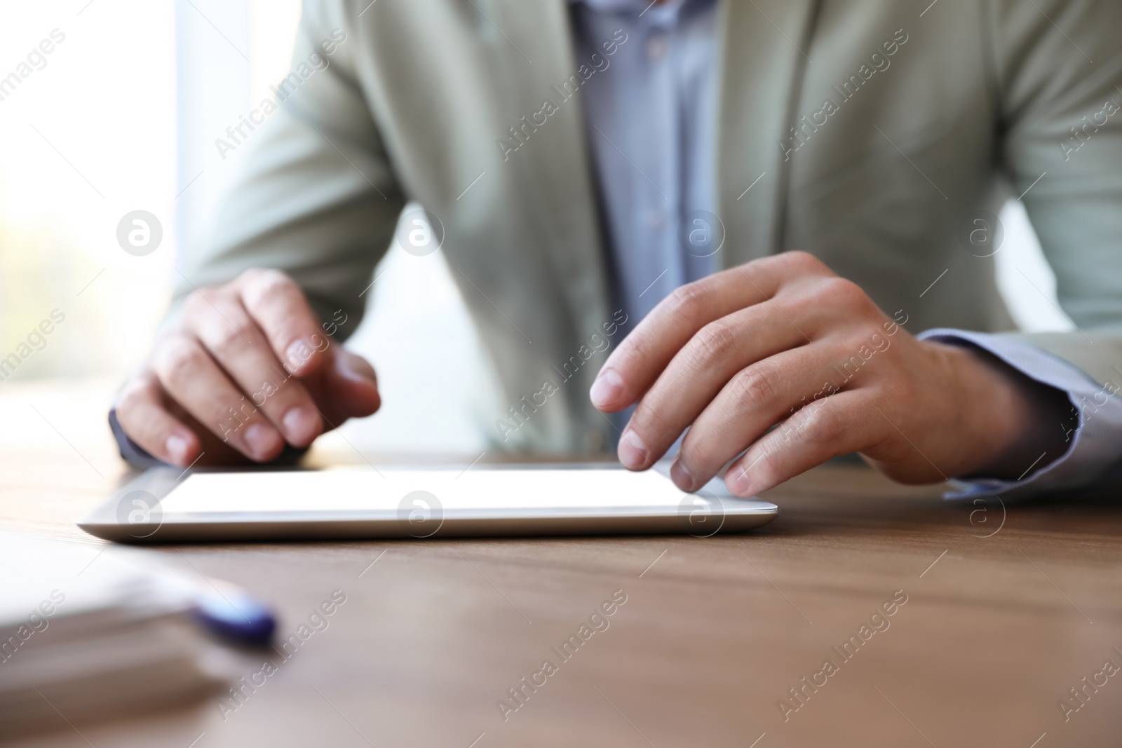 Photo of Businessman working with modern tablet at wooden table in office, closeup