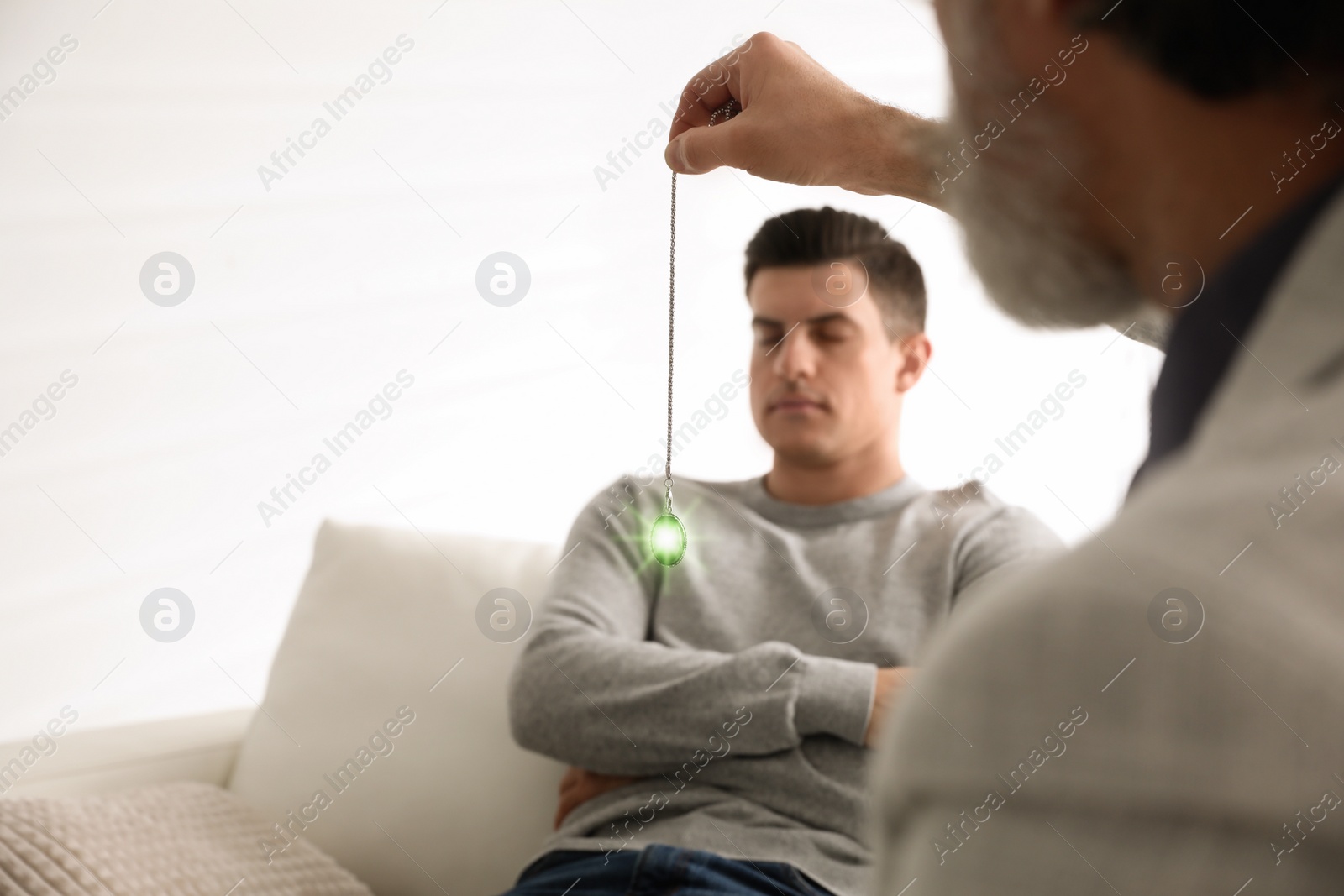 Photo of Psychotherapist using pendulum during hypnotherapy   session in office