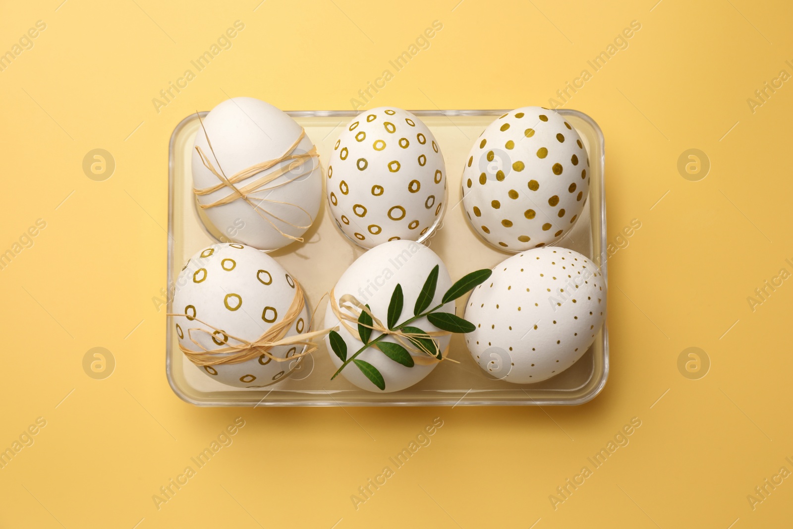 Photo of Festively decorated chicken eggs on yellow background, top view. Happy Easter