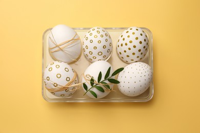 Photo of Festively decorated chicken eggs on yellow background, top view. Happy Easter