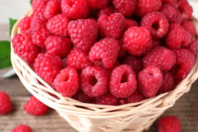 Tasty ripe raspberries in wicker basket on table, closeup