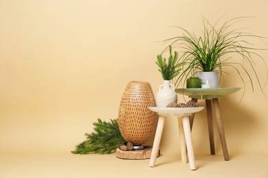 Decorative tables with candles and plants on beige background, space for text