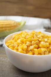 Photo of Bowl of preserved corn on wooden table