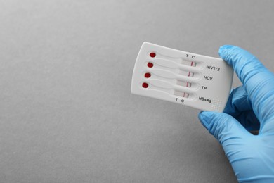 Photo of Doctor holding disposable multi-infection express test on light grey background, closeup. Space for text