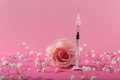 Photo of Cosmetology. Medical syringe, rose and gypsophila flowers on pink background