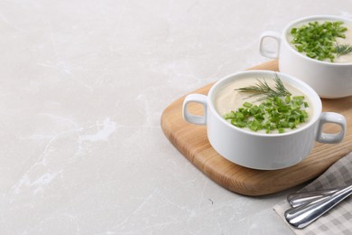 Photo of Bowls with tasty creamy soup of parsnip on light grey table, space for text