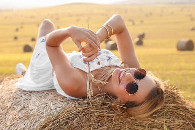 Photo of Beautiful hippie woman with spikelets on hay bale in field