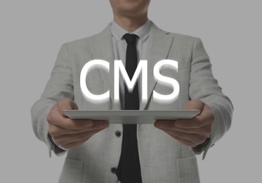 Image of CMS. Man with tablet on light grey background, closeup