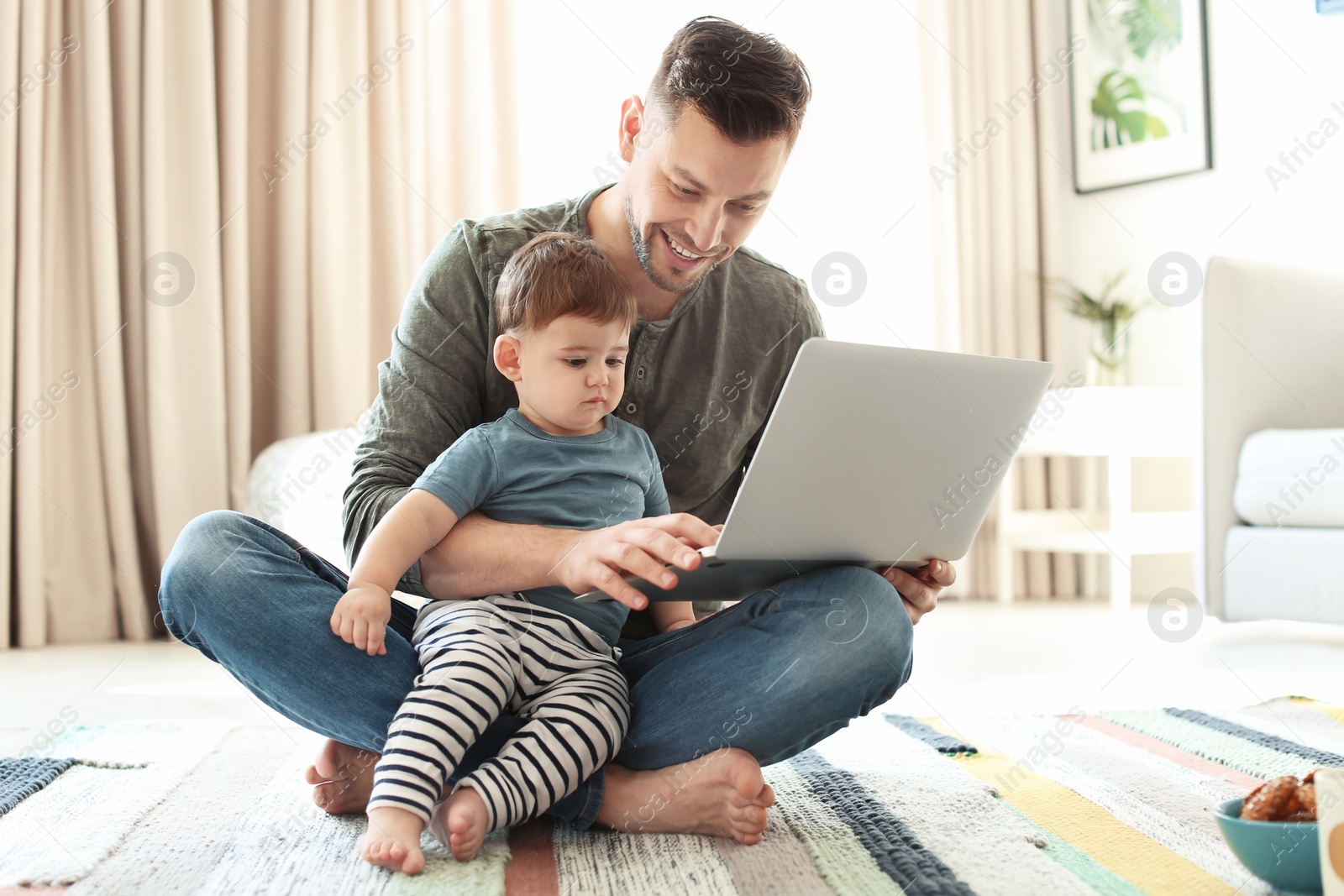 Photo of Dad and his son with laptop on carpet at home