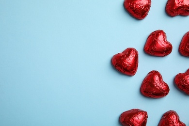 Photo of Heart shaped chocolate candies on light blue background, flat lay with space for text. Valentine's day treat