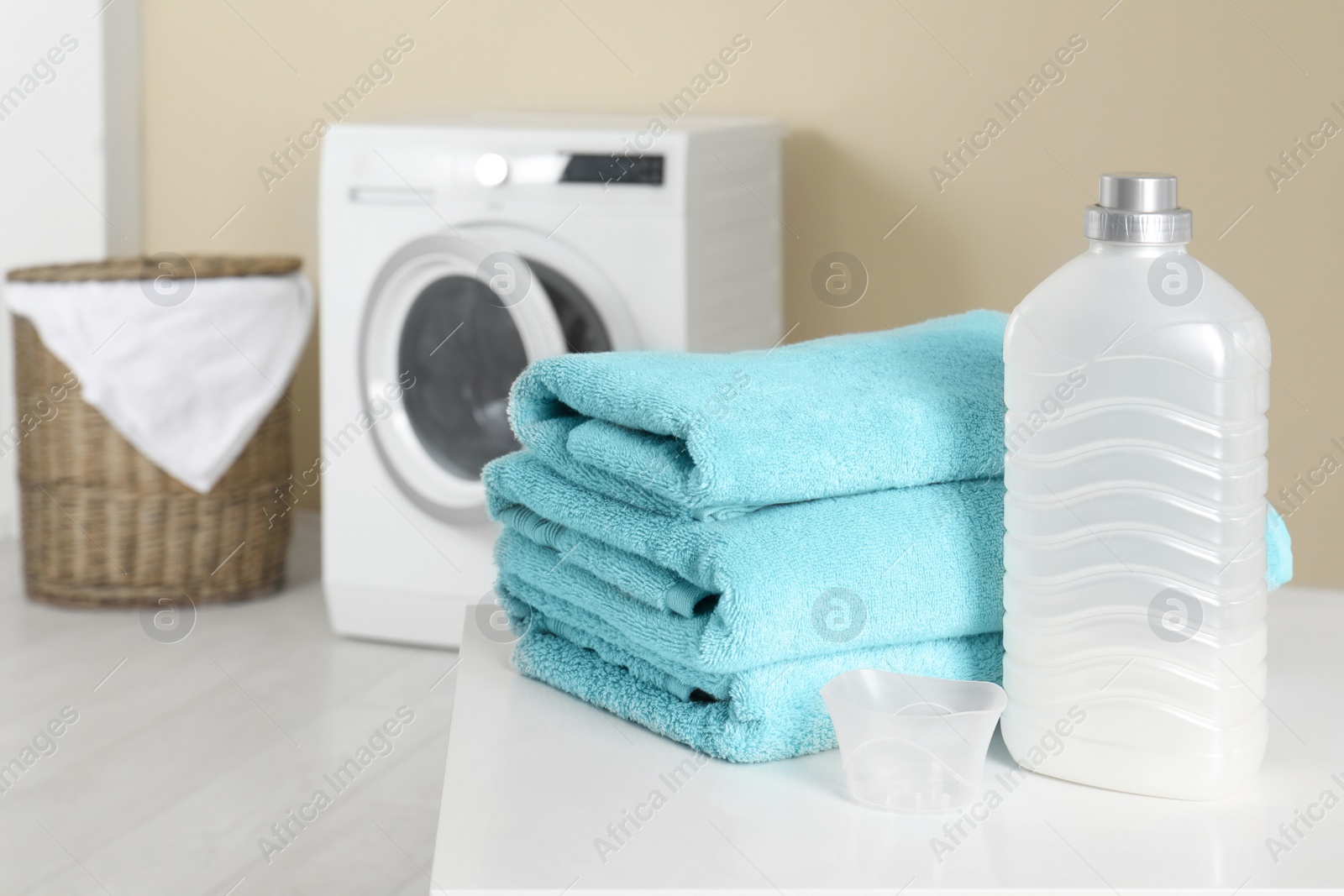 Photo of Stack of clean towels and detergent on table in laundry room. space for text