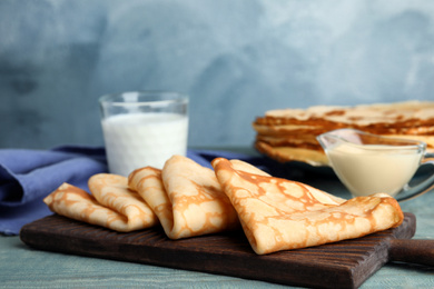 Photo of Fresh thin pancakes on blue wooden table