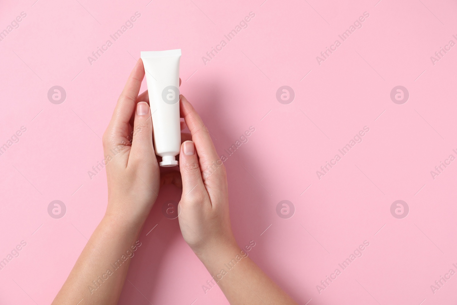 Photo of Woman with tube of hand cream on pink background, top view. Space for text