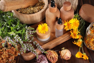 Jar, bottles of essential oils and different herbs on wooden table