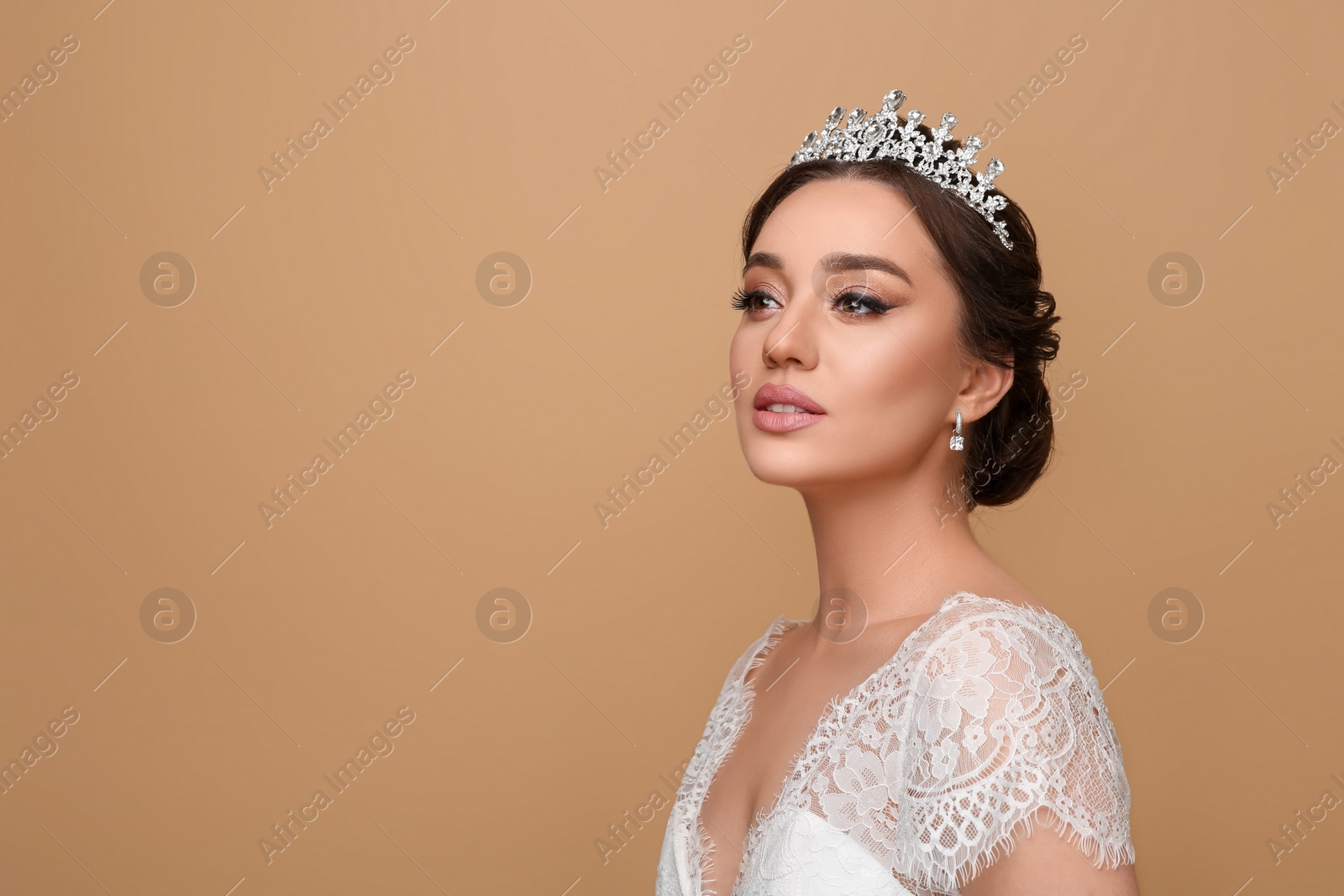 Photo of Beautiful young woman wearing luxurious tiara on beige background, space for text