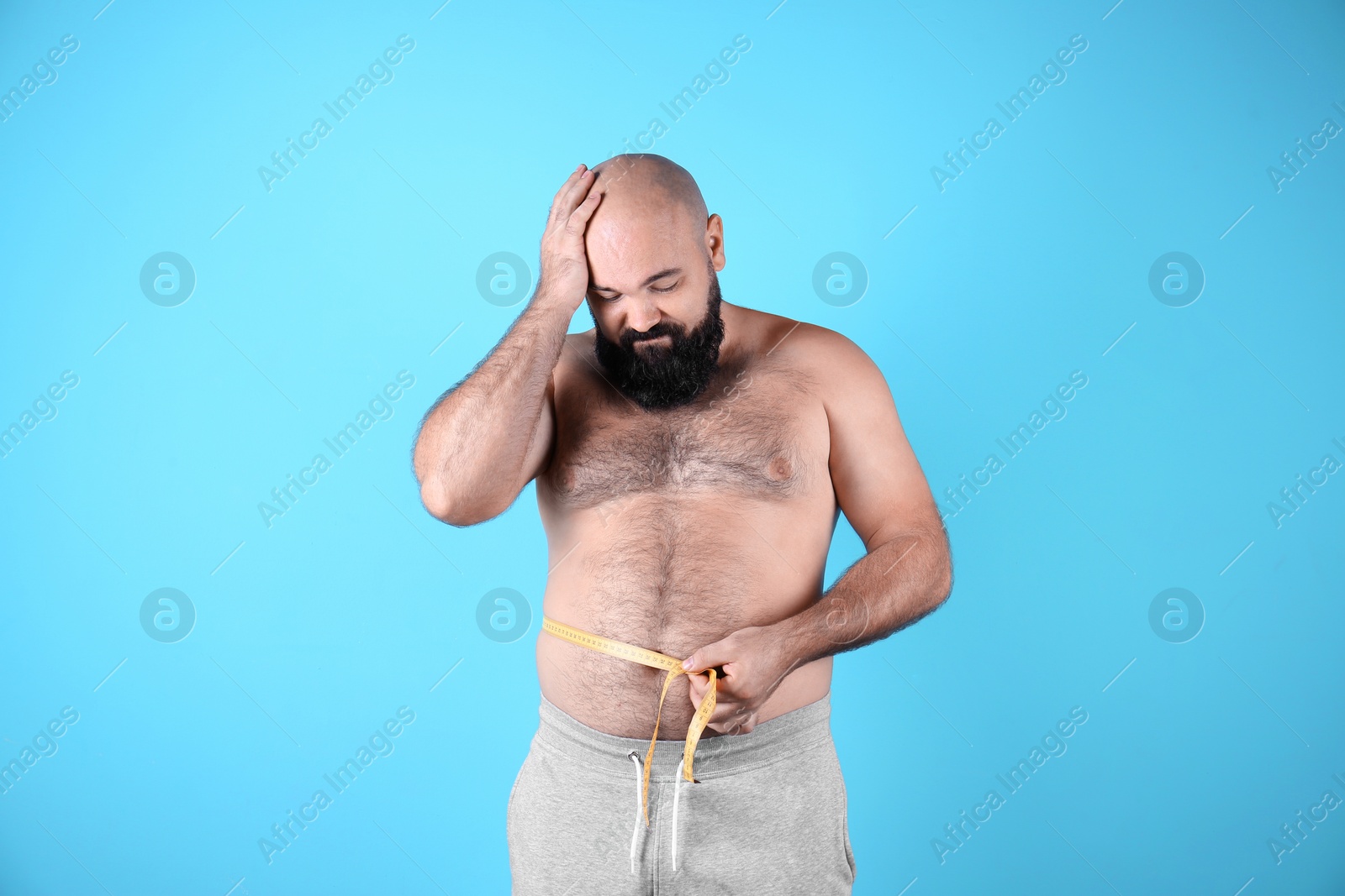 Photo of Fat man with measuring tape on color background. Weight loss