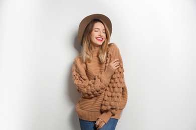 Photo of Beautiful young woman in warm sweater with hat on white background