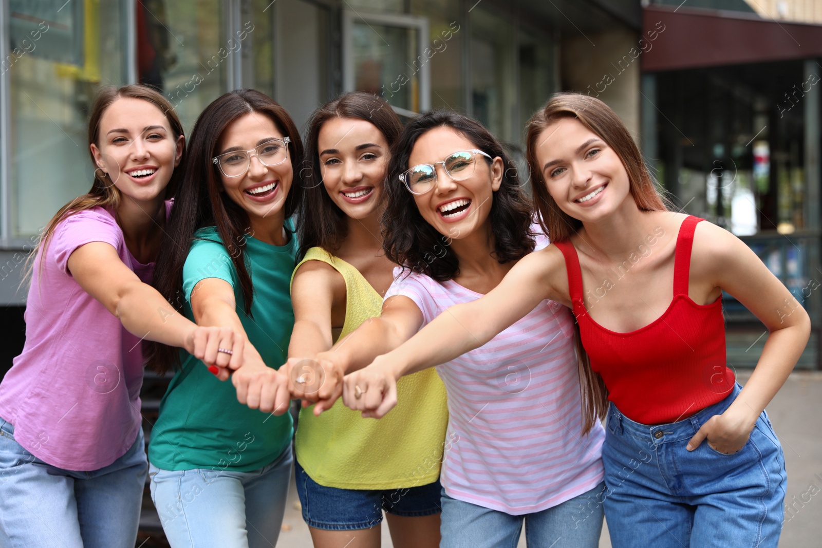 Photo of Happy women putting hands together outdoors on sunny day. Girl power concept