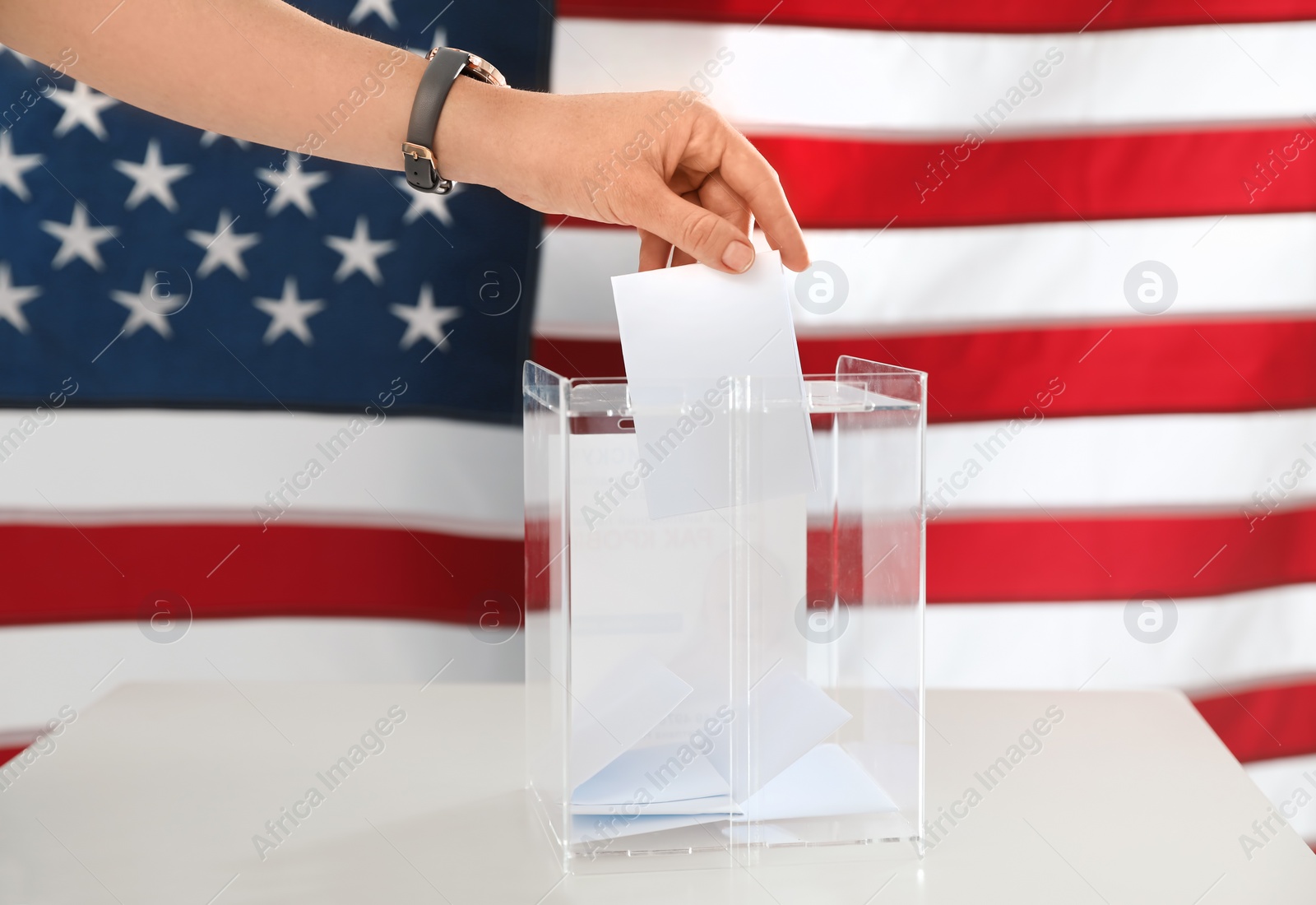 Photo of Woman putting ballot paper into box and American flag on background, closeup