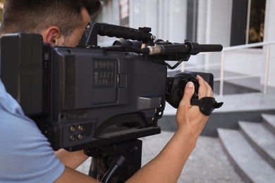 Professional video camera operator working on city street, closeup