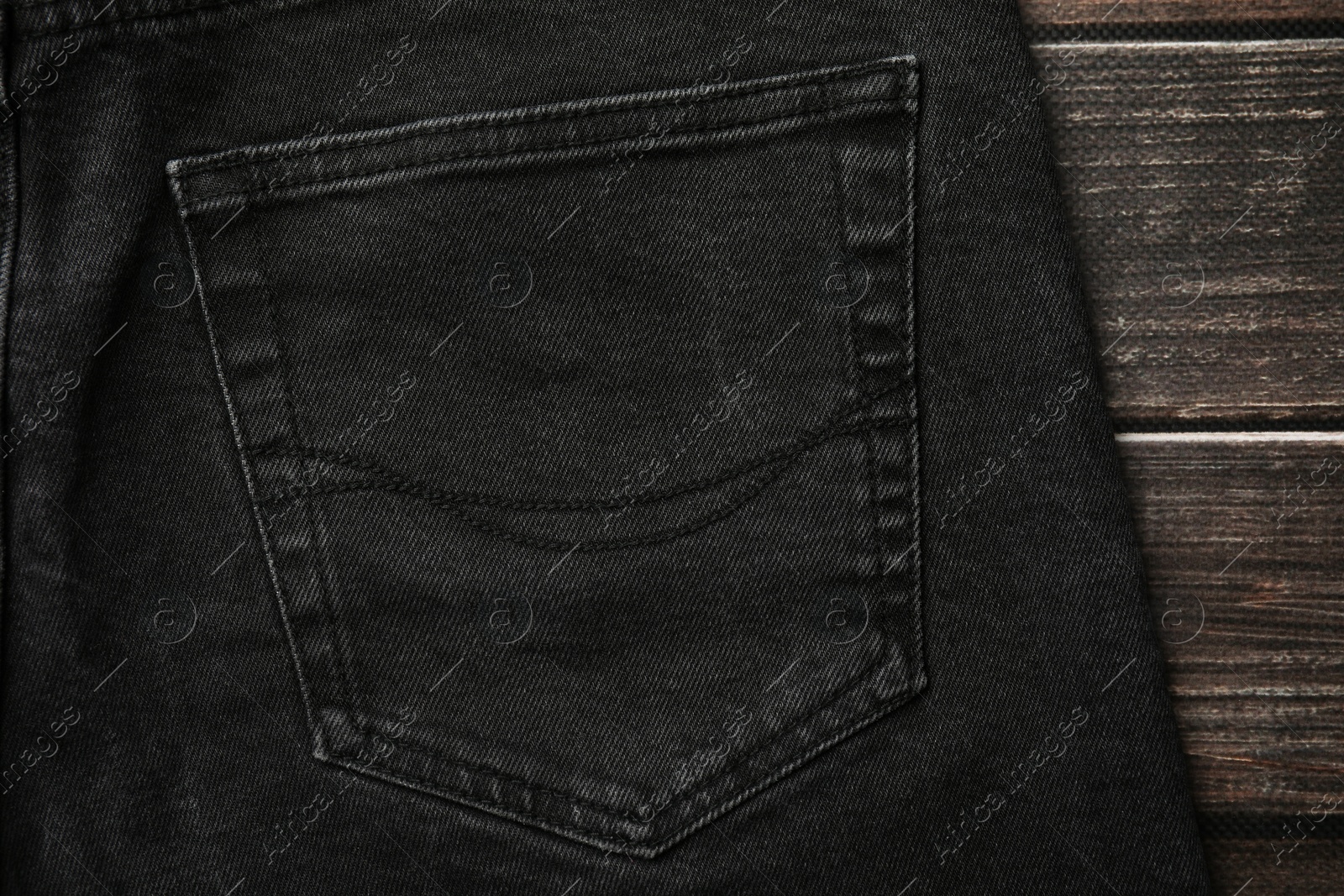 Photo of Black jeans with pocket on wooden background, top view