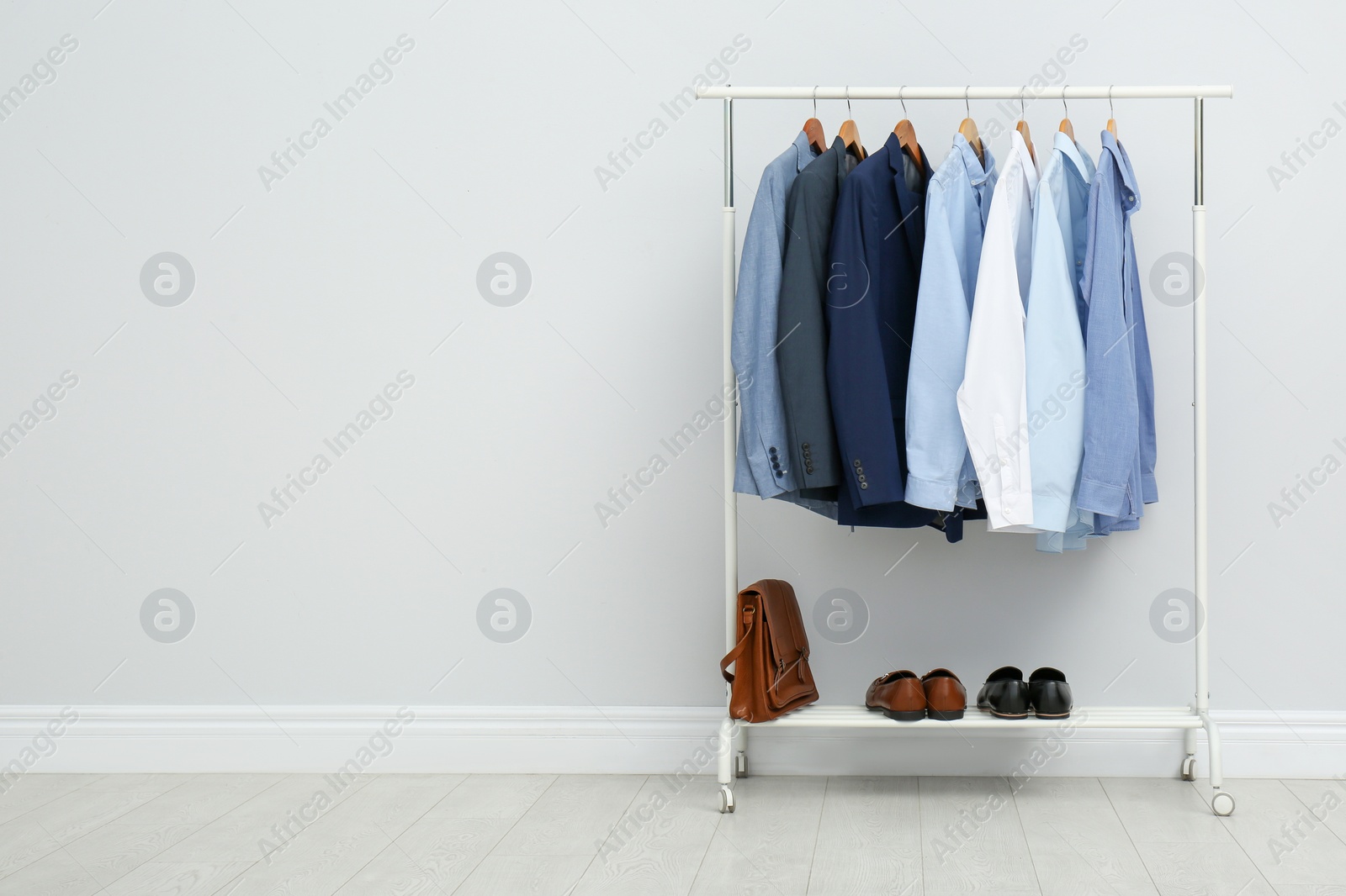 Photo of Rack with stylish men's clothes in room. Space for text