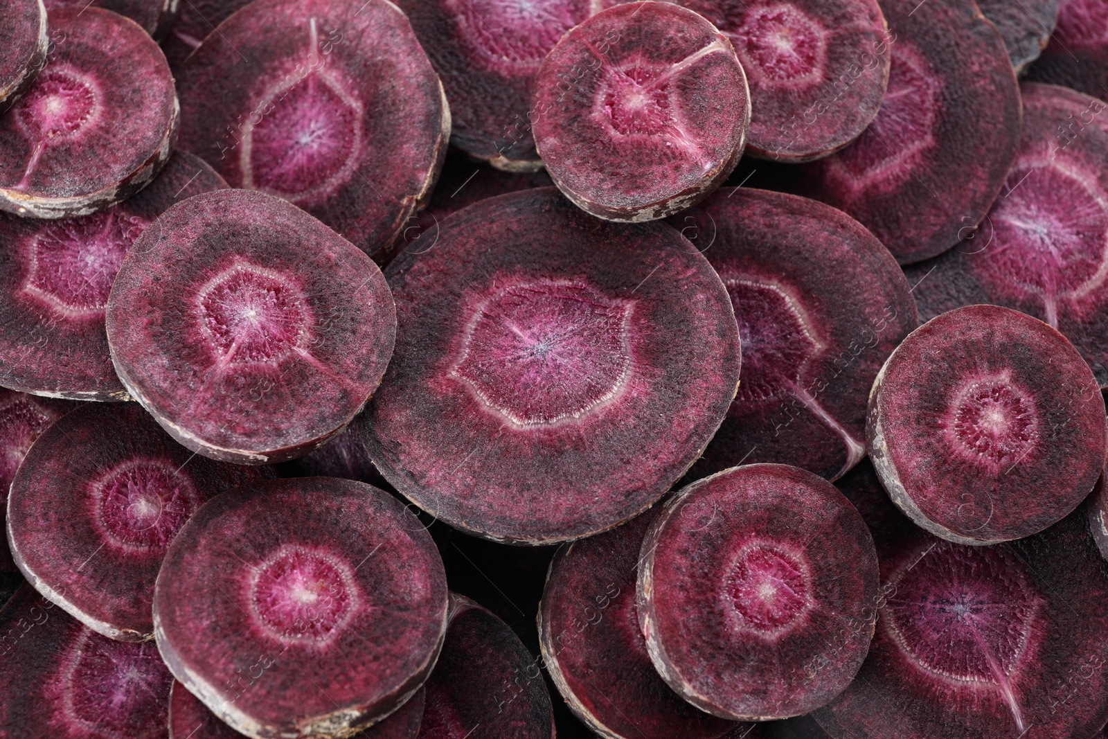 Photo of Slices of raw purple carrot as background, closeup