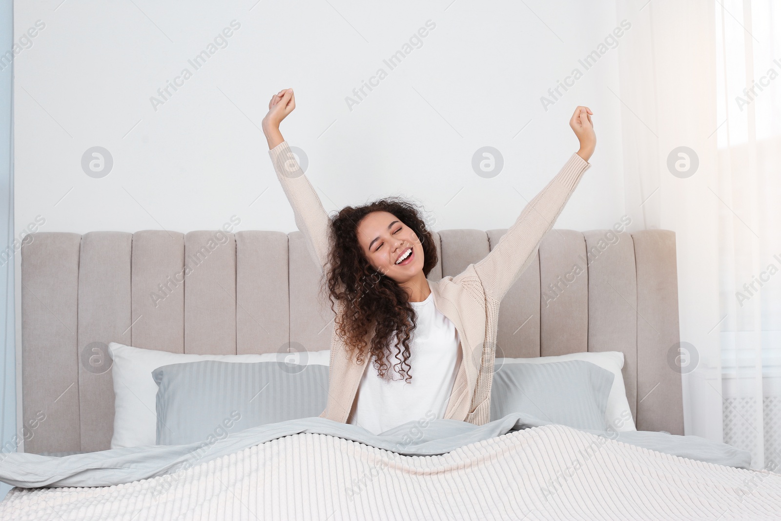 Photo of Beautiful African American woman stretching in bed at home