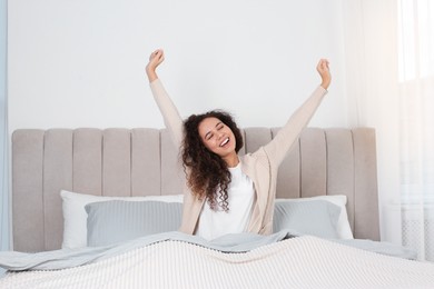 Photo of Beautiful African American woman stretching in bed at home