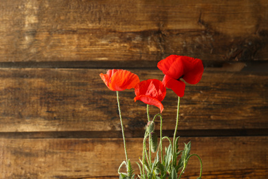 Photo of Beautiful red poppy flowers on wooden background