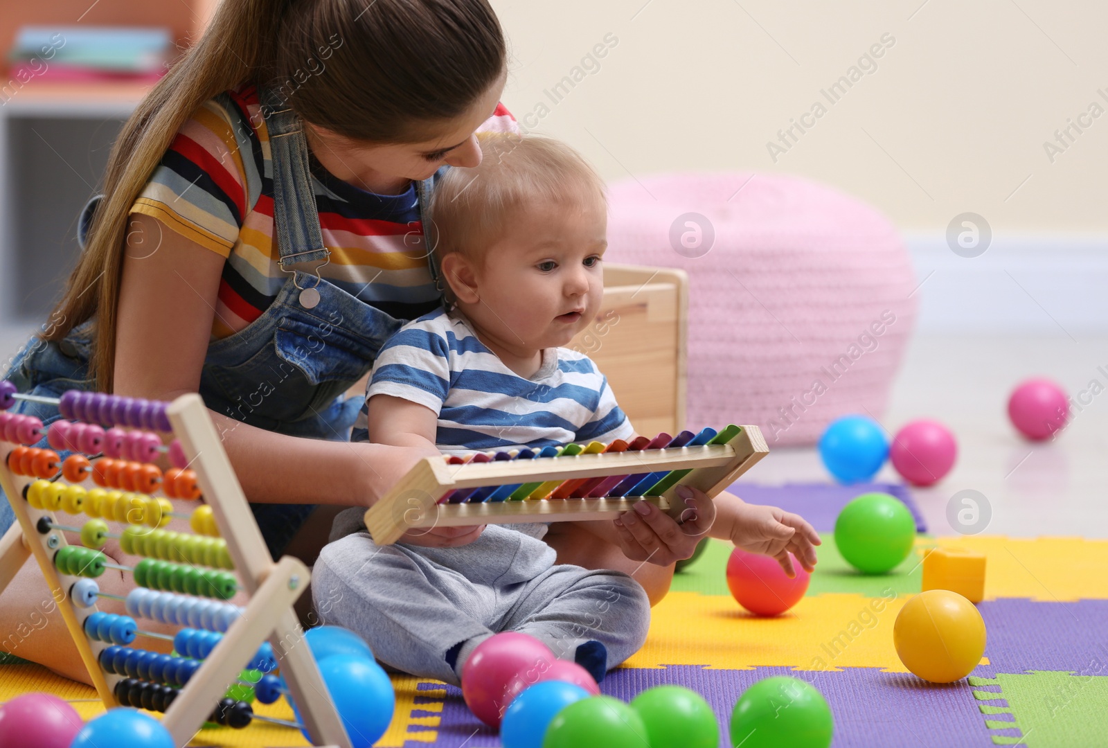 Photo of Teen nanny and cute little baby playing with xylophone at home