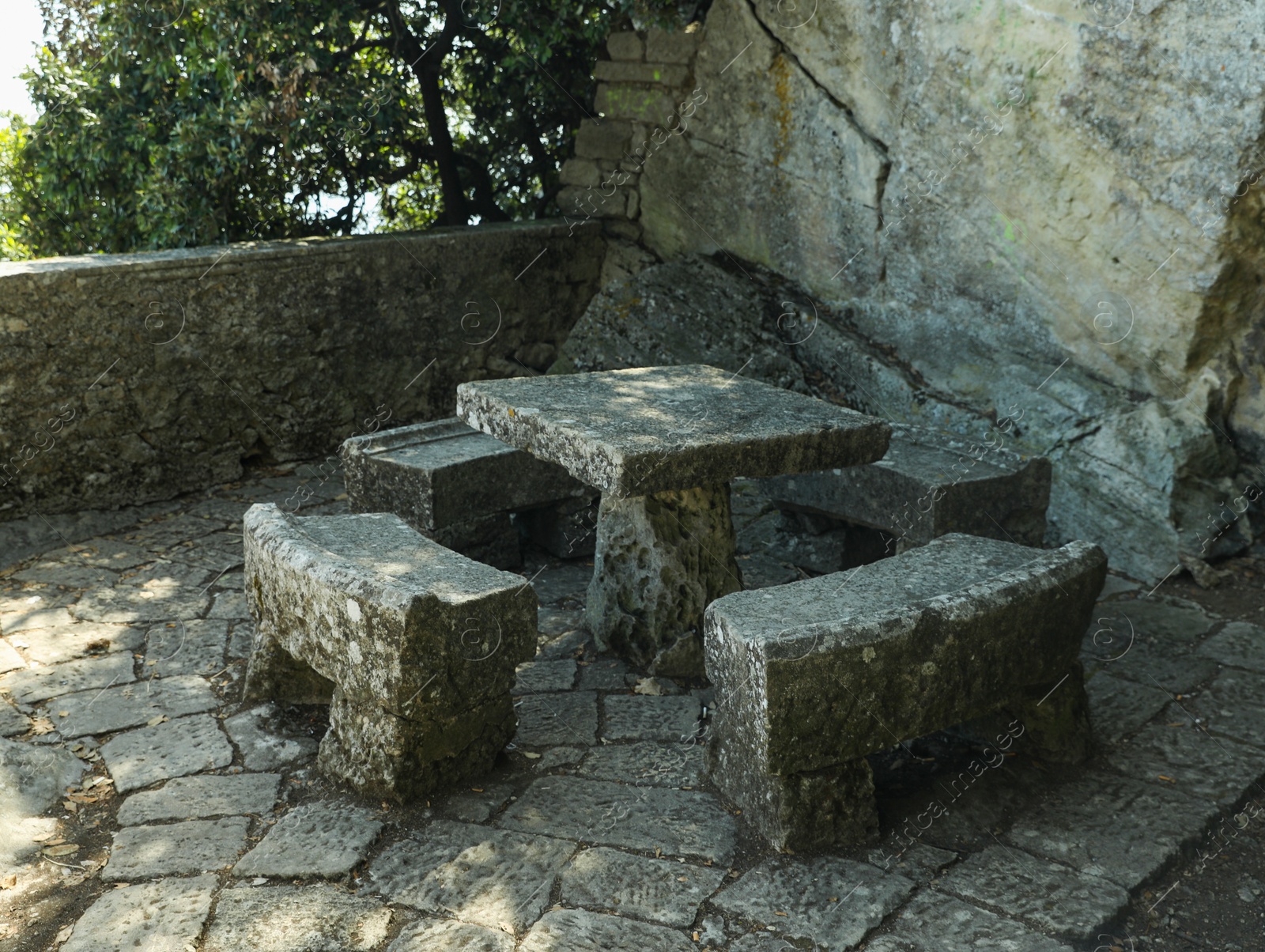 Photo of Stone table and benches near rock outdoors