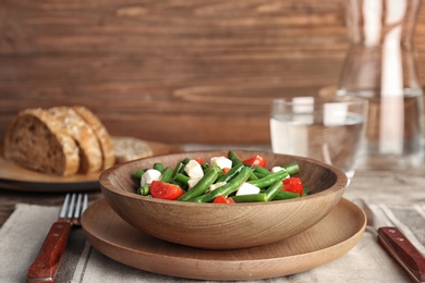 Plate with tasty green beans, tomatoes and cheese on table