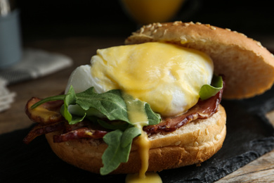 Photo of Delicious egg Benedict served on slate board, closeup