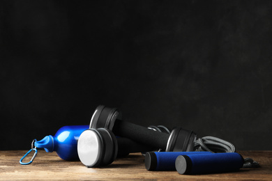 Photo of Gym equipment and accessories on floor against dark background. Space for text