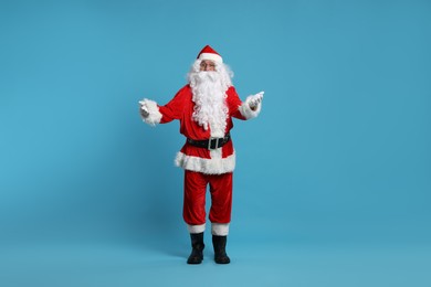 Photo of Merry Christmas. Santa Claus posing on light blue background
