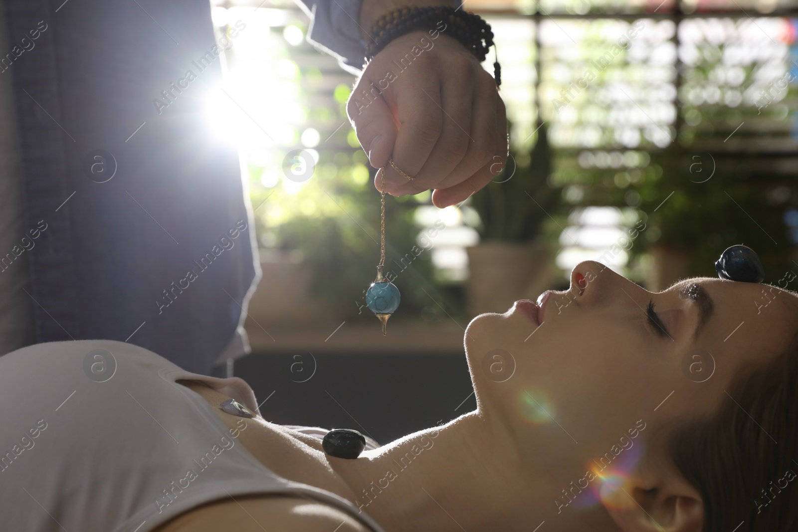 Photo of Young woman during crystal healing session in therapy room