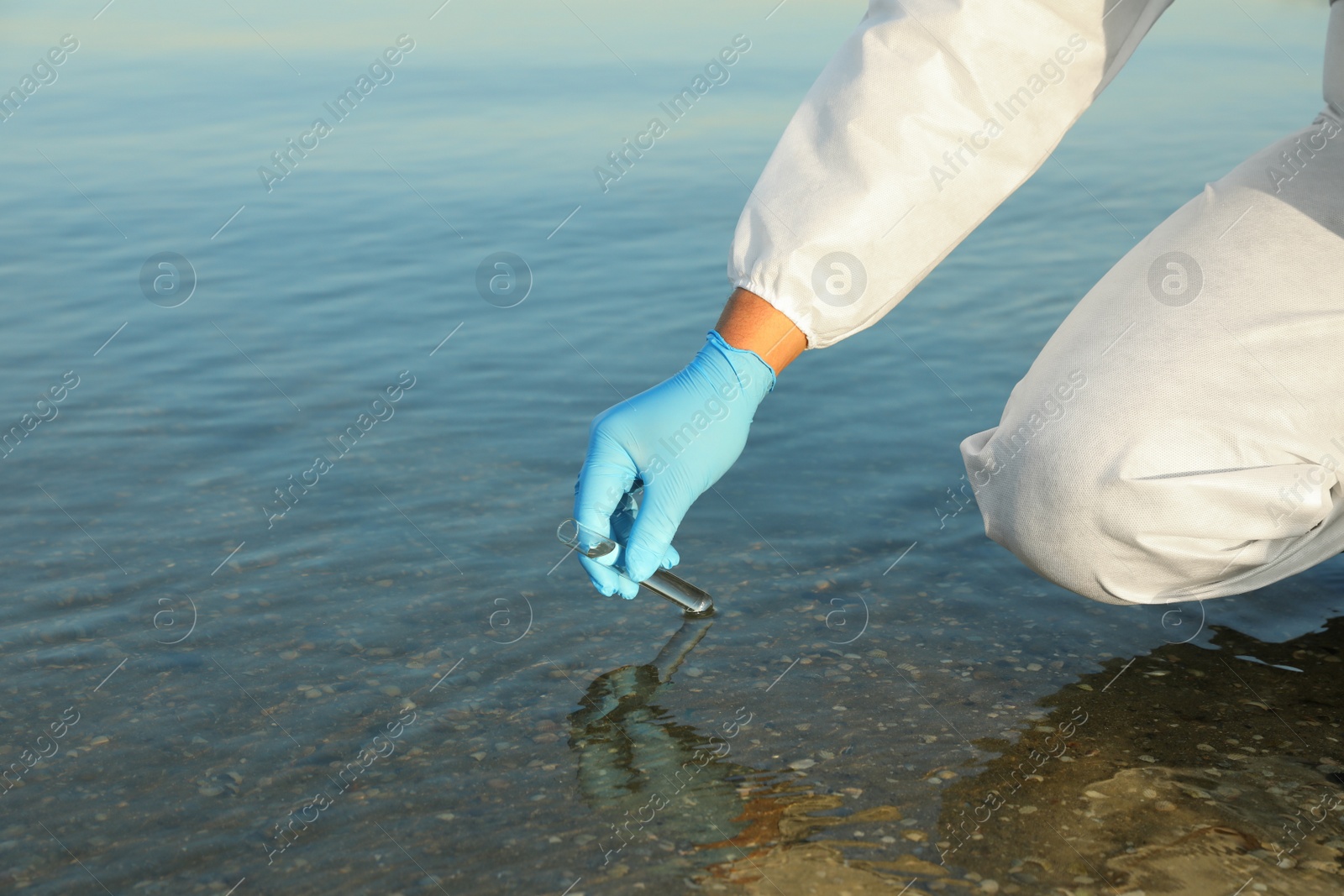 Photo of Scientist with test tube taking sample from river for analysis, closeup
