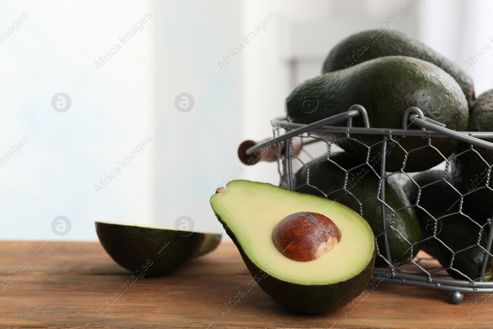 Photo of Delicious ripe avocados on wooden table against light background