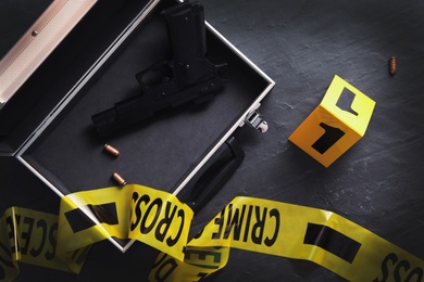Photo of Flat lay composition with evidences and crime scene tape on black slate background