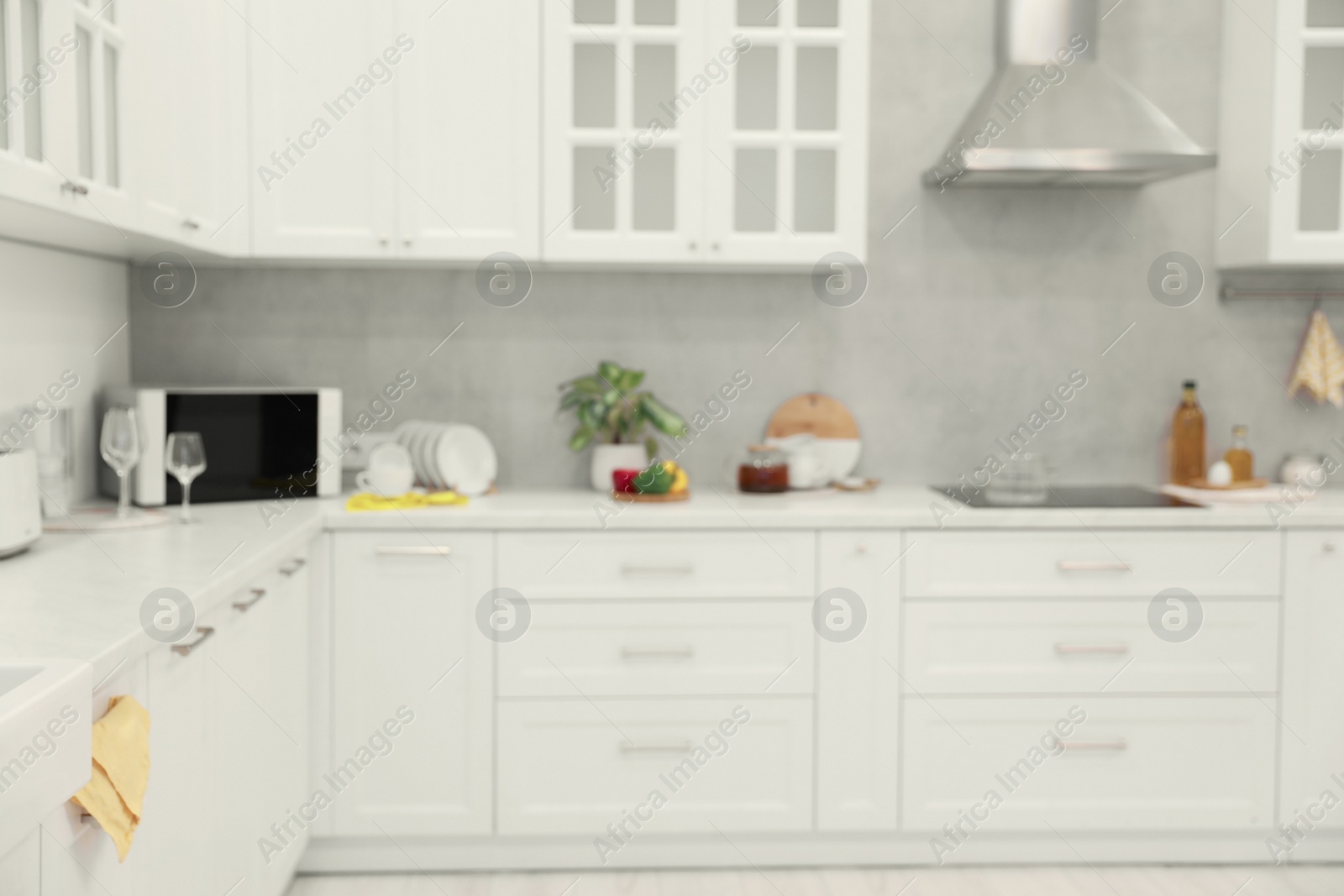 Photo of White cosy kitchen with furniture, blurred view. Interior design