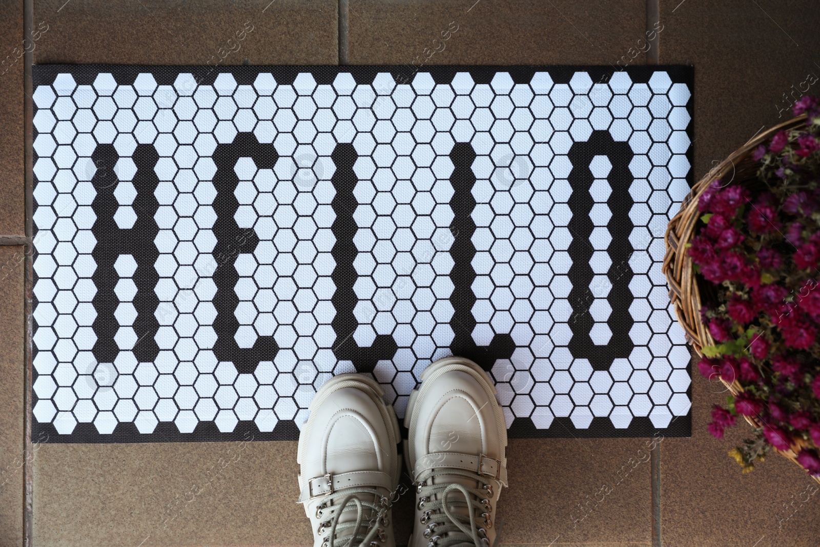 Photo of Stylish door mat with word Hello, shoes and beautiful flowers, flat lay