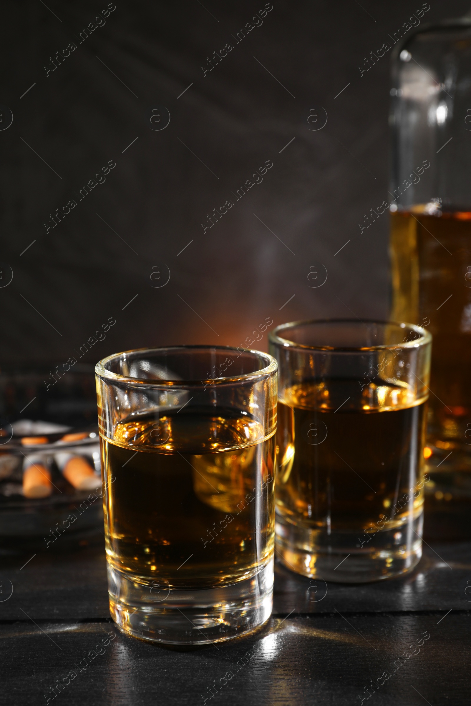 Photo of Alcohol addiction. Whiskey in glasses on black wooden table