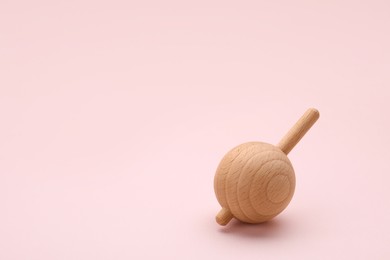 Photo of One wooden spinning top on beige background, space for text. Toy whirligig
